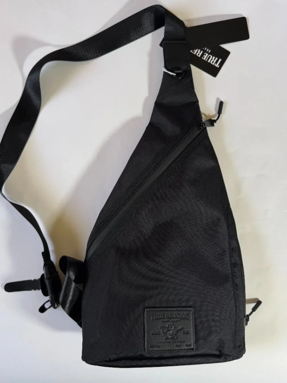 True Religion Black Sling Bag Features a Textured Black Logo Patch on the Front